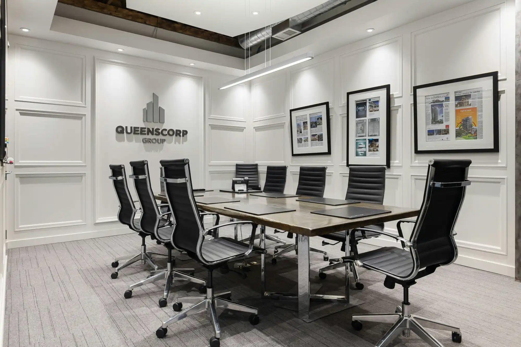 Modern conference table with black leather executive chairs arranged around it.